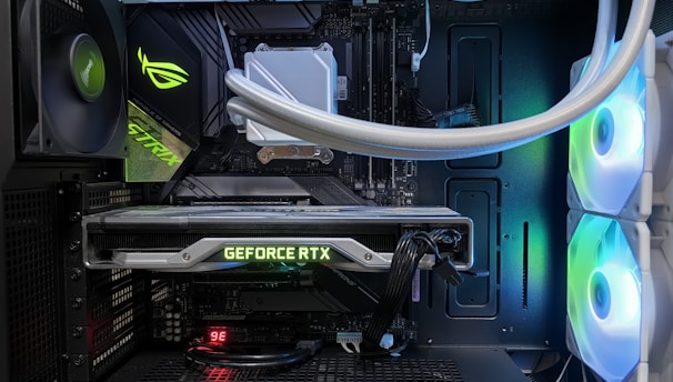 A high-end gaming or performance PC interior equipped with RGB lighting and multiple cooling fans. The graphics card prominently displayed is a GeForce RTX model, with branding visible. The setup includes neatly managed cables and a liquid cooling system.